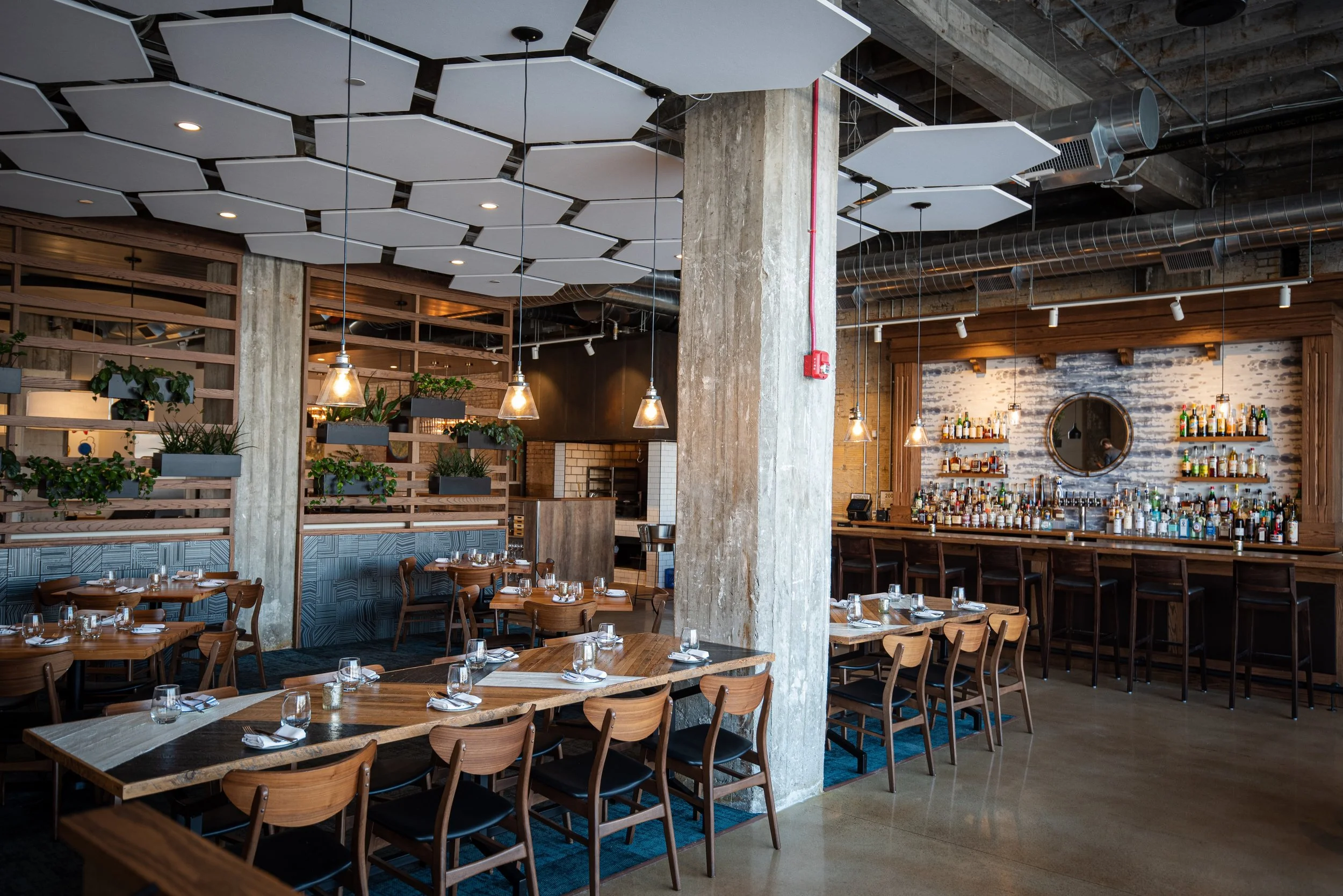 Oak & Reel dining room with warm wood, concrete, and blue seating